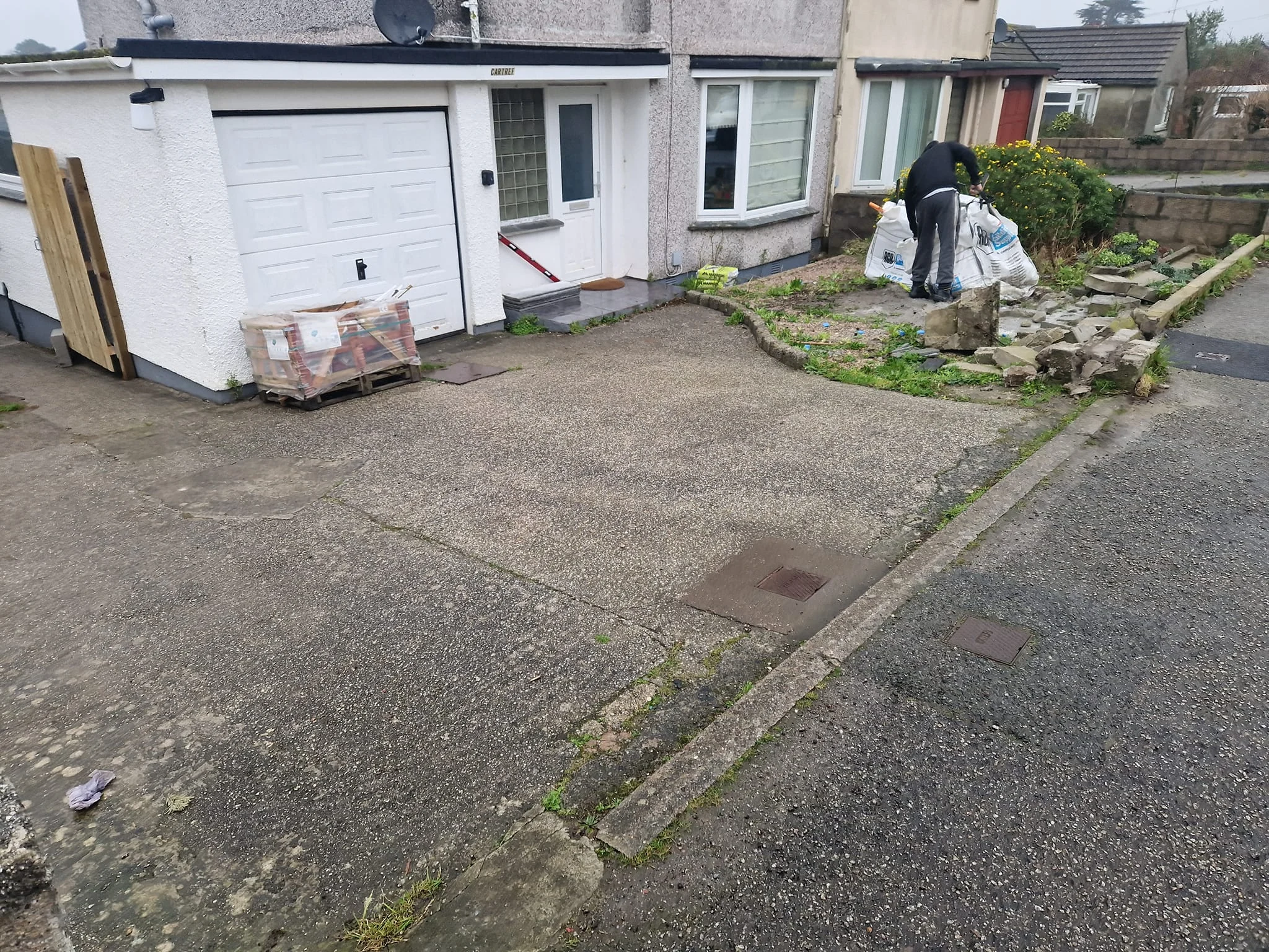 Cracked concrete driveway in front of a white garage, before work