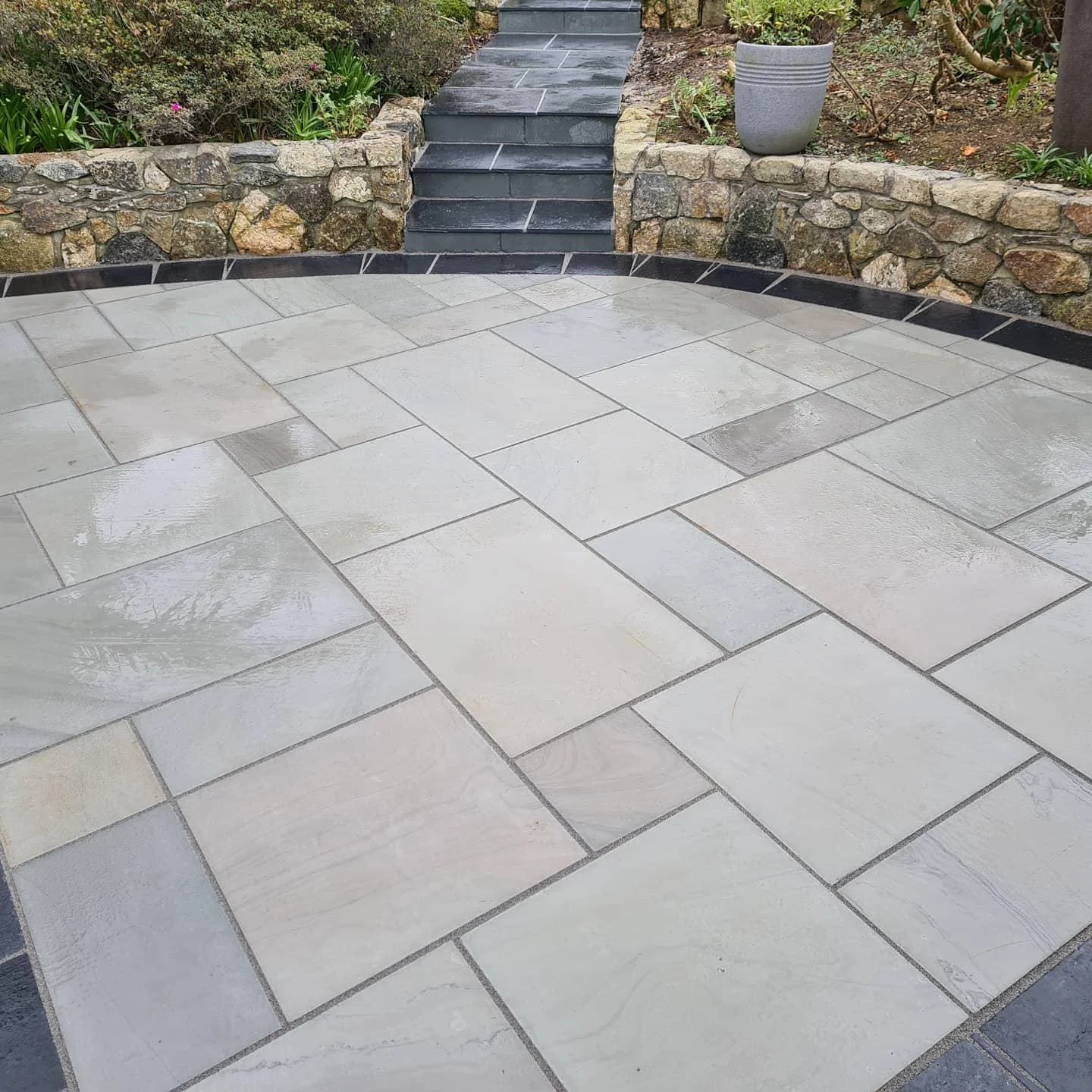 Sandstone patio with a raised natural stone wall